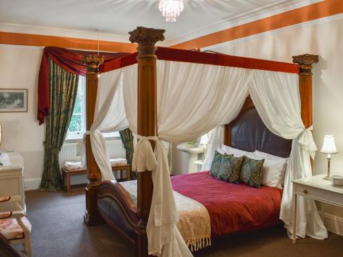 a bedroom with a canopy bed with a red comforter at Calthwaite Hall West Wing in Calthwaite