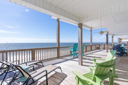 a deck with chairs and the ocean in the background at Waves of Grace in Dauphin Island