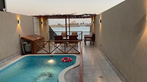 ein Schwimmbad mit einem roten Floß in einem Haus in der Unterkunft درة العروس فيلا بشاطئ رملي خاص in Durrat Al-Arus
