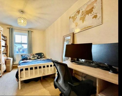 a bedroom with a desk with a computer and a bed at Cosy 2 bedroom appartment with gated parking by River Thames in Kingston upon Thames