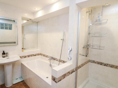 a bathroom with a shower and a tub and a sink at Leeward in Dartmouth