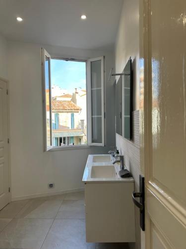 baño blanco con lavabo y ventana en Le Mourillonnais en Toulon
