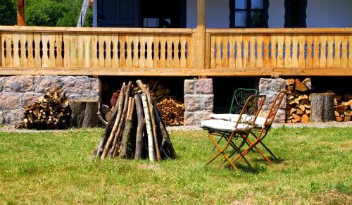 a chair and a pile of logs in front of a house at Dobrica Hunting Lodge in Bixad
