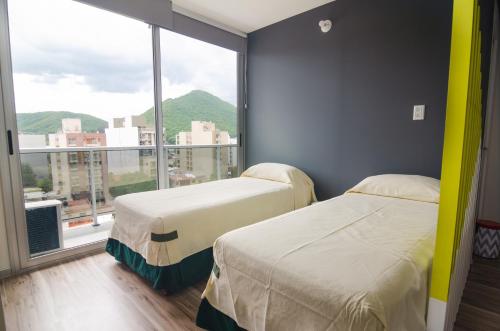 2 Betten in einem Zimmer mit einem großen Fenster in der Unterkunft DA DFC in Salta