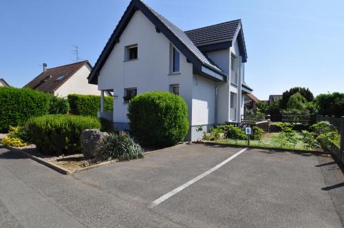 a white house with a parking lot at Aux cigognes de Blotzheim in Blotzheim