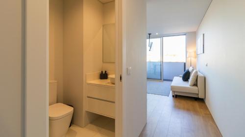 a bathroom with a toilet and a sink and a couch at Nice Circunvalação Studio II By Unique Hosts in Senhora da Hora