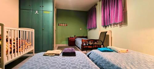哈爾基斯的住宿－Kounis Villa，卧室设有两张床铺、绿色墙壁和婴儿床