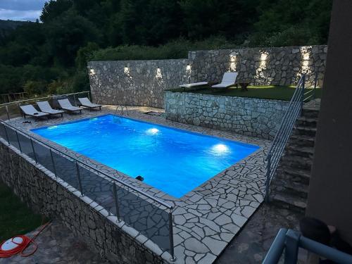a swimming pool with chairs and a stone wall at Brioni in Virpazar