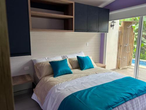 a bedroom with a large bed with blue pillows at Subtropica Premium Suites - Mindo in Mindo
