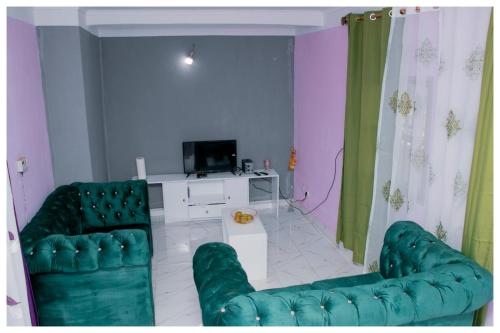 uma sala de estar com duas cadeiras verdes e uma televisão em RÉSIDENCE COLETTE em Bafoussam