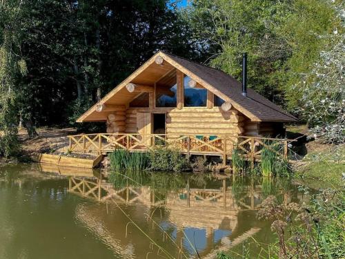 a log cabin next to a body of water at Log Cabin/Hot Tub on Private Lake Jurassic Coast in Bridport