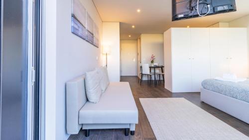 a living room with a white chair and a bed at Nice Circunvalação Studio I By Unique Hosts in Senhora da Hora