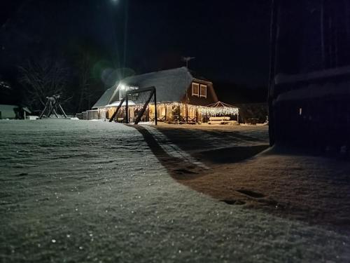 un granero de noche con nieve en el suelo en Trainiškio pirkia en Ginučiai