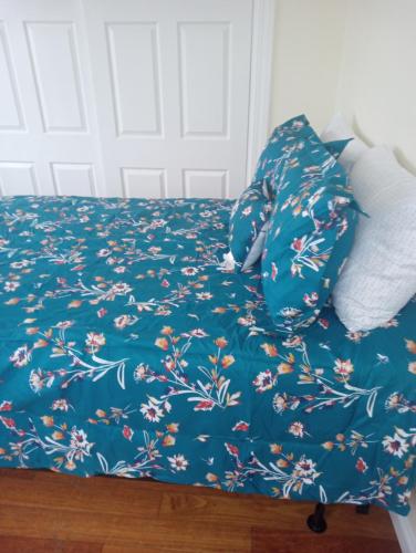 a bed with a blue blanket with flowers on it at One bedroom with free parking in Schenectady