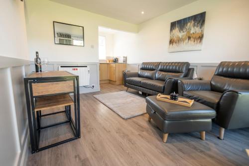 a living room with leather furniture and a table at Find peace in a chalet by the beach in Kessingland