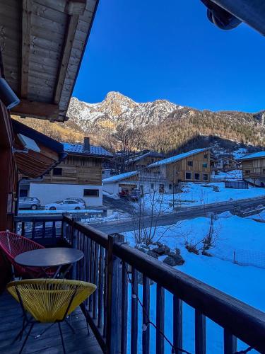 d'un balcon avec une table, des chaises et des montagnes enneigées. dans l'établissement Chalet La Savoyarde, à Peisey-Nancroix