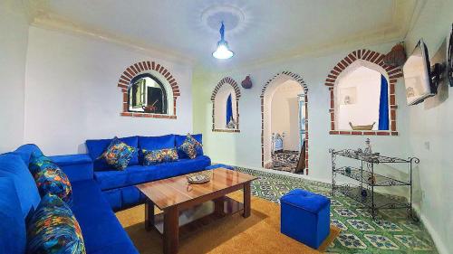 a living room with a blue couch and a table at Dar La Aicha in Chefchaouen