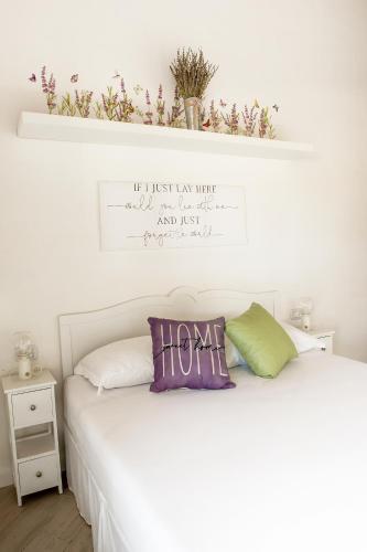 a bedroom with a white bed with flowers on the wall at Love Nests by The Bell Tower Lodge in Palidoro