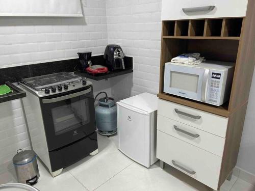 a small kitchen with a microwave and a stove at Flat Completo in Vila Velha