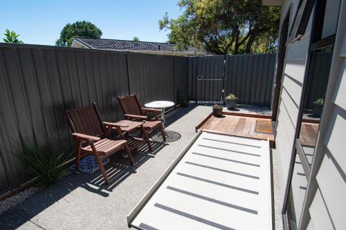 a patio with two chairs and a table and a fence at Middle Park Motel in Blenheim