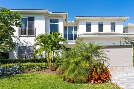 una gran casa blanca con palmeras delante en VILLA MAGNOLIA-with heated pool-by VIAC, en Fort Lauderdale
