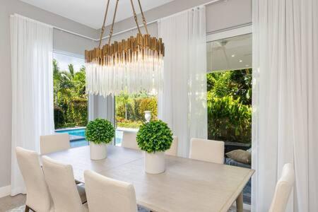 a dining room with a table and chairs and a chandelier at VILLA MAGNOLIA-with heated pool-by VIAC in Fort Lauderdale