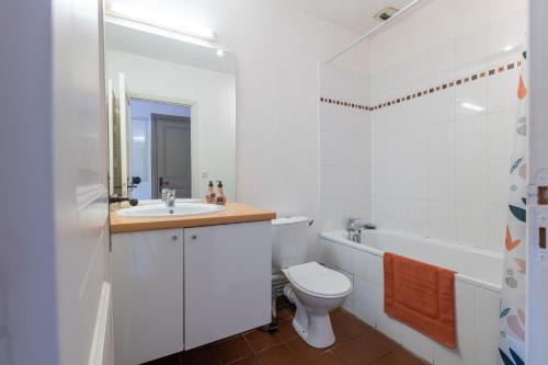 une salle de bain blanche avec des toilettes et un lavabo dans l'établissement Bel Appartement avec cour au cœur de la Bastide, à Carcassonne