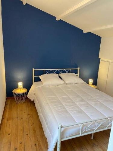 une chambre avec un lit avec un mur bleu dans l'établissement L'Aréna - Logement cosy proche des arènes, à Nîmes