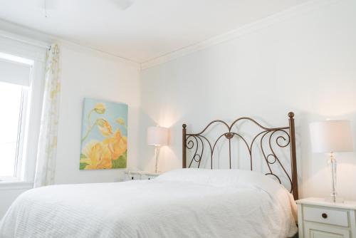 a white bedroom with a large bed and two lamps at Auberge Incroyable in Saint Adrien