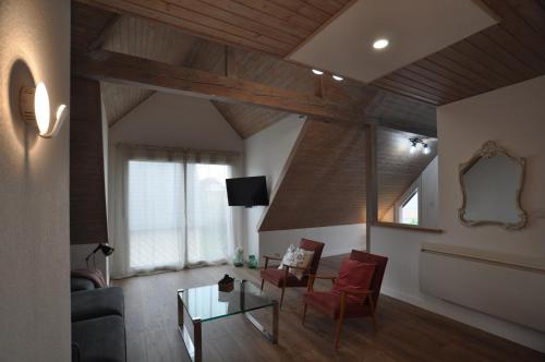 a living room with a table and red chairs at L'Hirondelle - Charming flat - in Blotzheim