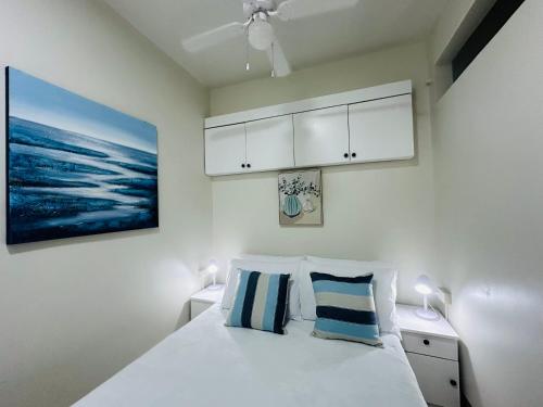 1 dormitorio con 1 cama blanca y 2 almohadas azules en Condo in MOA, en Manila