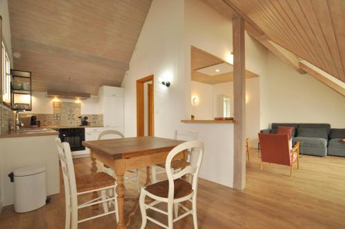 eine Küche und ein Wohnzimmer mit einem Holztisch und Stühlen in der Unterkunft L'Hirondelle - Charming flat - in Blotzheim