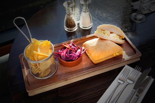 a sandwich on a cutting board with chips and a salad at Holiday Inn Stoke on Trent M6 Jct15, an IHG Hotel in Stoke on Trent