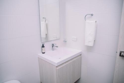 uma casa de banho branca com um lavatório e um espelho em Apartaestudio Luxur en Barranquilla em Barranquilla