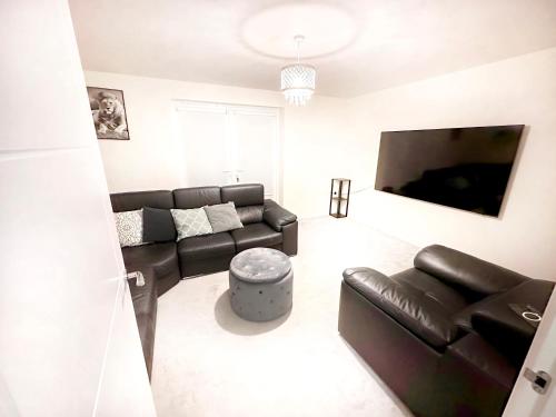 a living room with a leather couch and a flat screen tv at Ensuite Room with free parking 