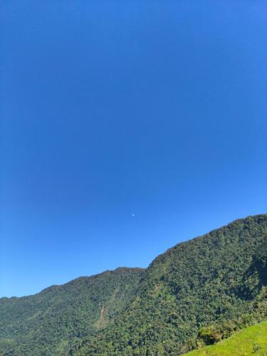 a green mountain with a blue sky in the background at Sierra de viboral adventures in Medellín