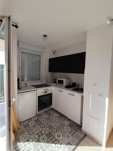 uma cozinha com armários brancos e um micro-ondas em t2 spacieux très bien place em Gagnac-sur-Garonne