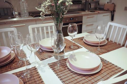 a table with glasses and plates and a vase with flowers at Breathtaking Sunsets Flat in Las Palmas de Gran Canaria