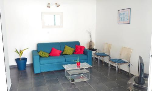 a blue couch with colorful pillows in a living room at Jasmin - Appartement face plage Diamant in Le Diamant