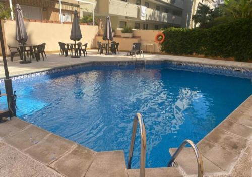 a large blue swimming pool with chairs and umbrellas at Piso céntrico con piscina y cochera Almuñecar in Almuñécar