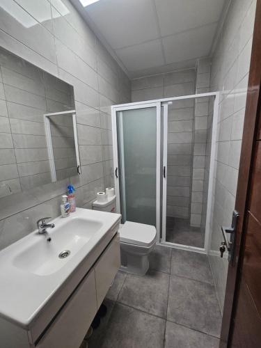 y baño con ducha, lavabo y aseo. en Appartement moderne près de la corniche, en Nador