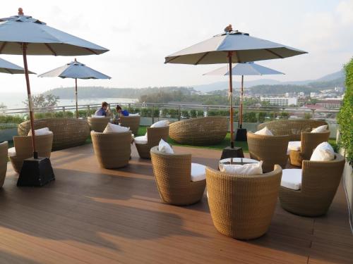 a patio with chairs and umbrellas on a roof at Sugar Palm Grand Hillside - SHA Plus in Kata Beach