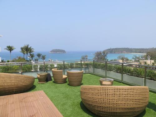 a patio with chairs and a table and the ocean at Sugar Palm Grand Hillside - SHA Plus in Kata Beach