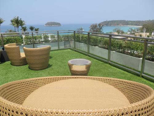 a rattan table and chairs on a balcony with the water at Sugar Palm Grand Hillside - SHA Plus in Kata Beach