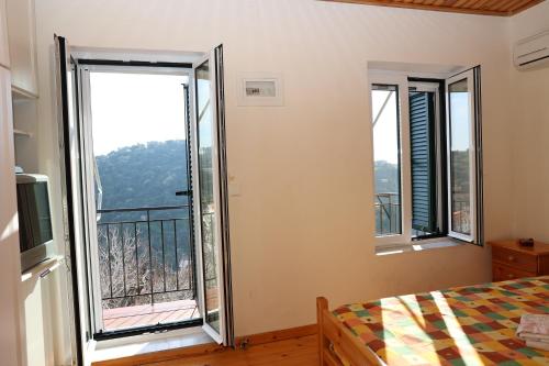 a bedroom with two windows and a bed and a balcony at Mary's Villas in Plomari