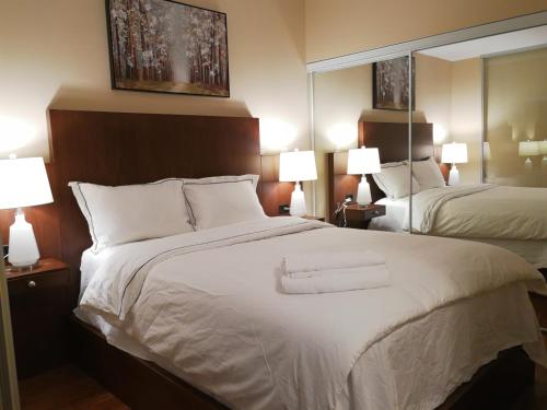 a hotel room with a large white bed and mirrors at Gorgeous Condo in Downtown Near CN Tower in Toronto