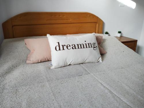 Una almohada con sueños escrita en ella sentada en una cama en La Brisa en Mar del Plata