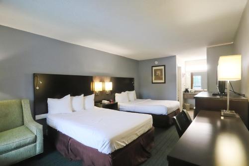 a hotel room with two beds and a chair at Greenville Inn & Suites in Greenville