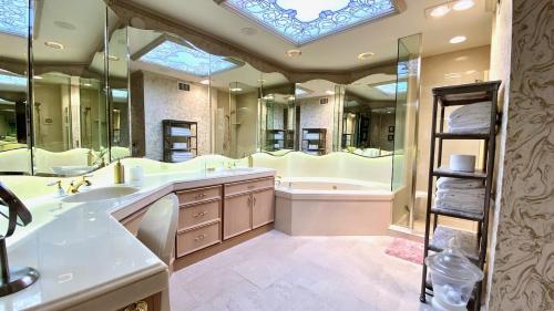 un bagno con due lavandini, una vasca e un grande specchio di LA DOLCE VITA VILLA 3 en-suites+large living spaces+glorious outdoor space:managed by Greenday a Rancho Mirage