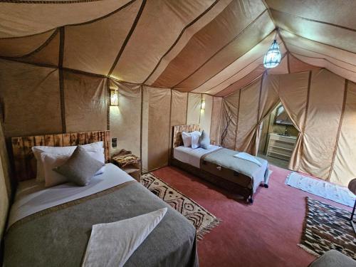 a bedroom with two beds in a tent at Najma Luxury Camp in Merzouga